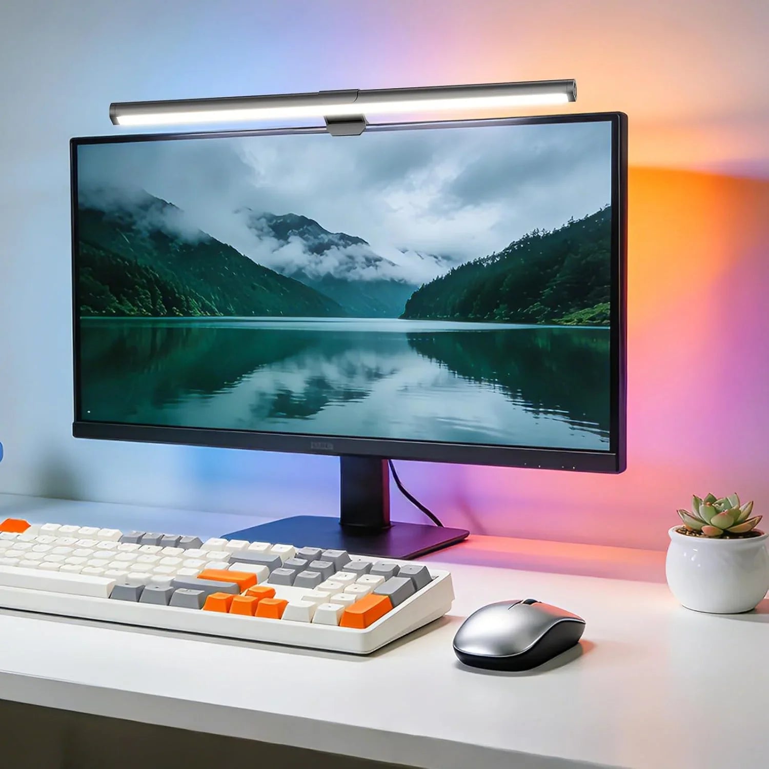 LED monitor light bar on computer screen with wireless keyboard, mouse, and small potted plant on desk