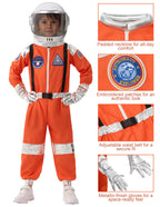 Child wearing orange astronaut costume with helmet, embroidered patches, metallic gloves, and adjustable belt.