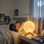 Child sleeping in a space-themed bedroom with a glowing moon lamp on bedside table