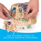 Hands using excavation tools to dig colorful gemstones from a sand block, educational toy set