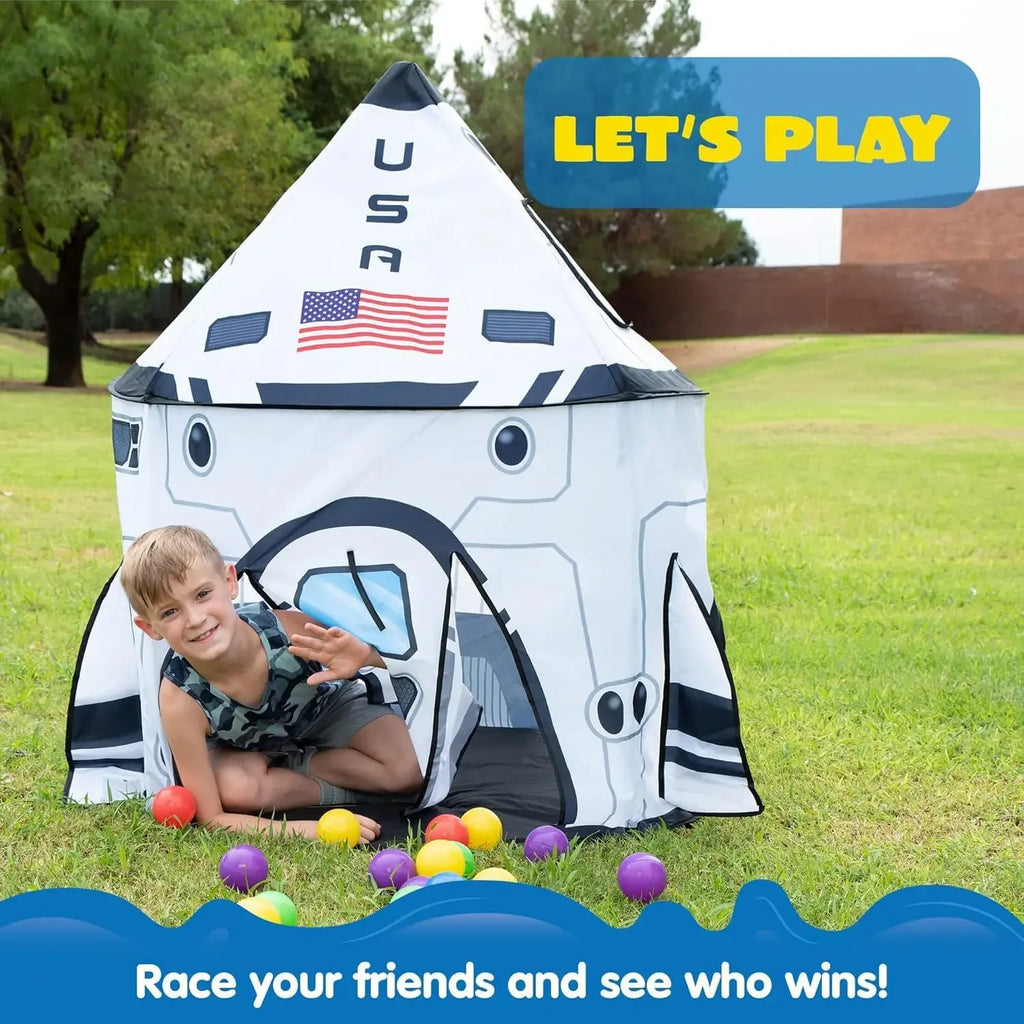 Boy playing in space rocket play tent with colorful balls outdoors, kids toy for imaginative play.
