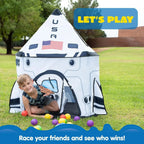 Boy playing in space rocket play tent with colorful balls outdoors, kids toy for imaginative play.