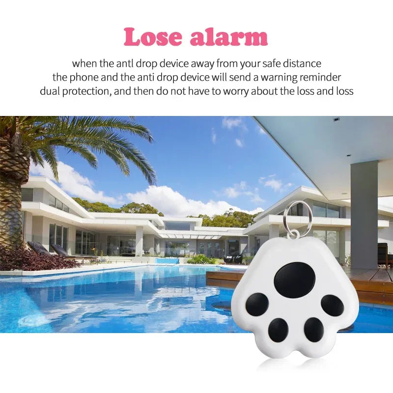 Paw-shaped anti-loss alarm keychain for pets or valuables, shown by a modern house with pool.