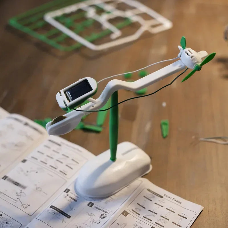 Solar-powered DIY science kit with moving propeller, assembly instructions visible on table.