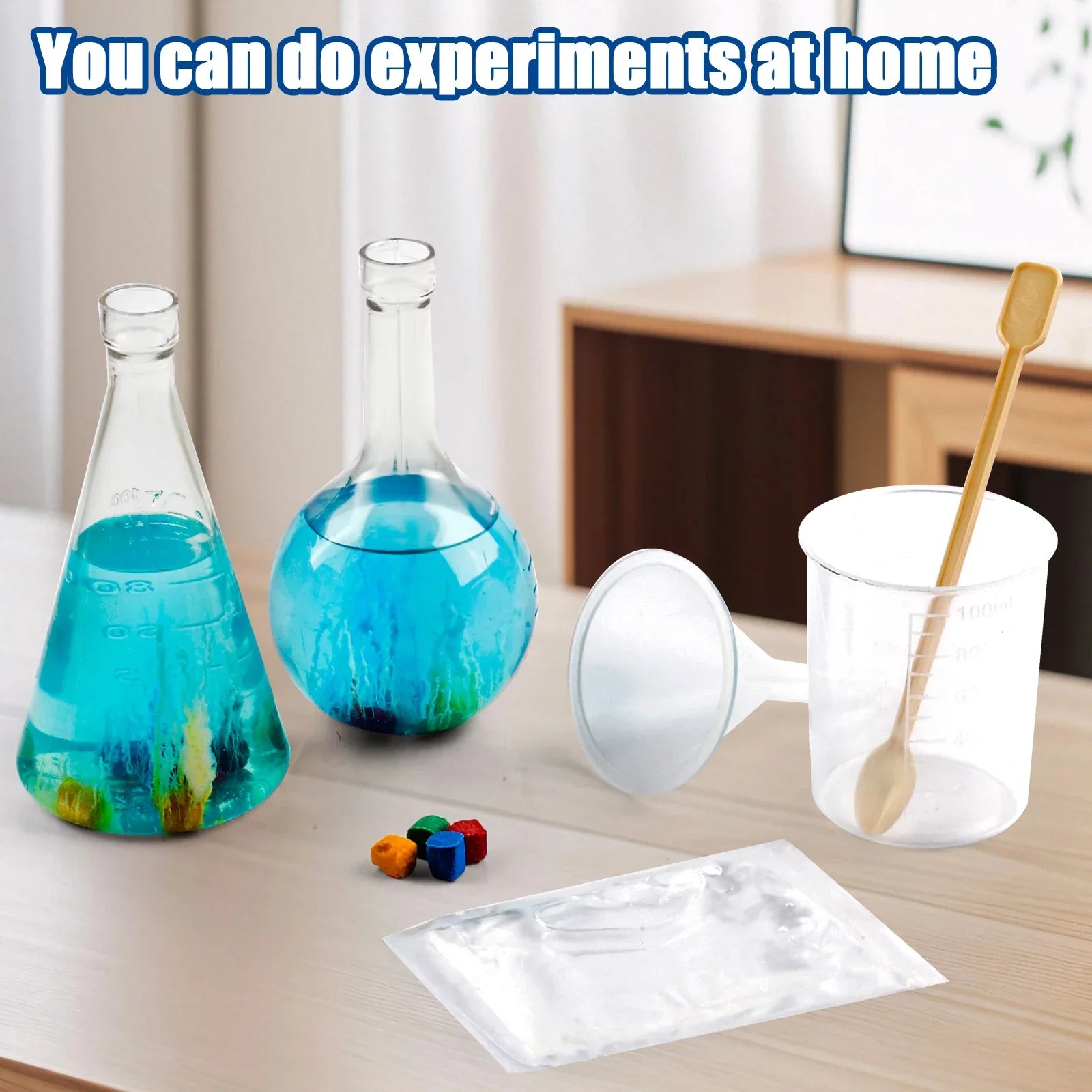 Home science experiment kit with beakers, blue liquid, mixing tools and colored tablets on table