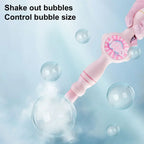 Pink bubble toy wand with gloved hand creating soap bubbles on blue background.